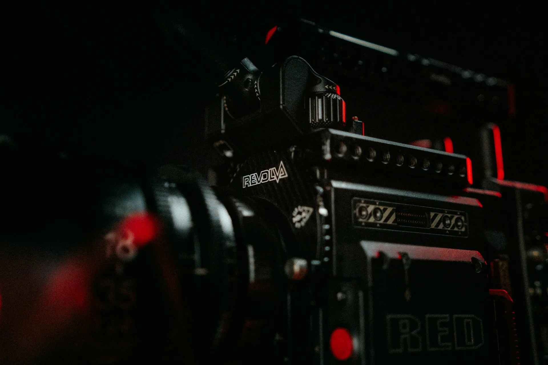 A cinema camera body in the dark, lit by small red lights