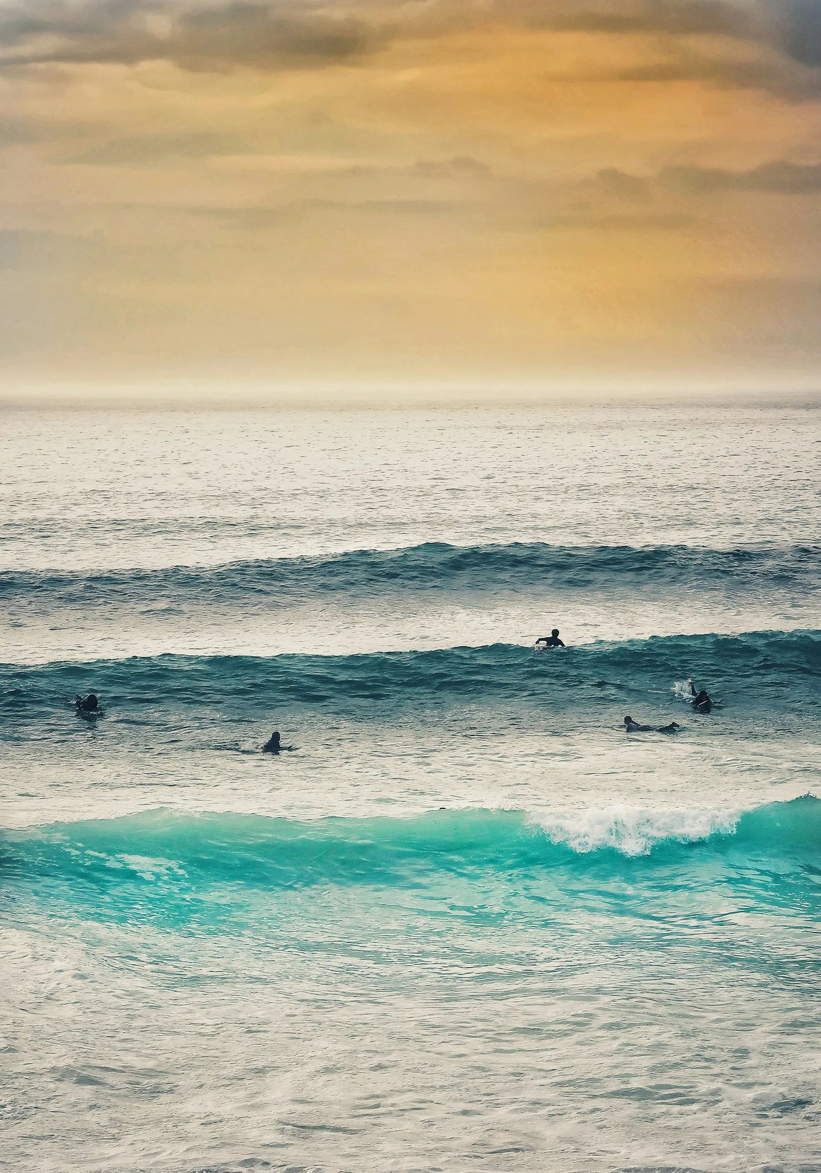 Surfers waiting for waves at Fistral Beach, Newquay, at sunset